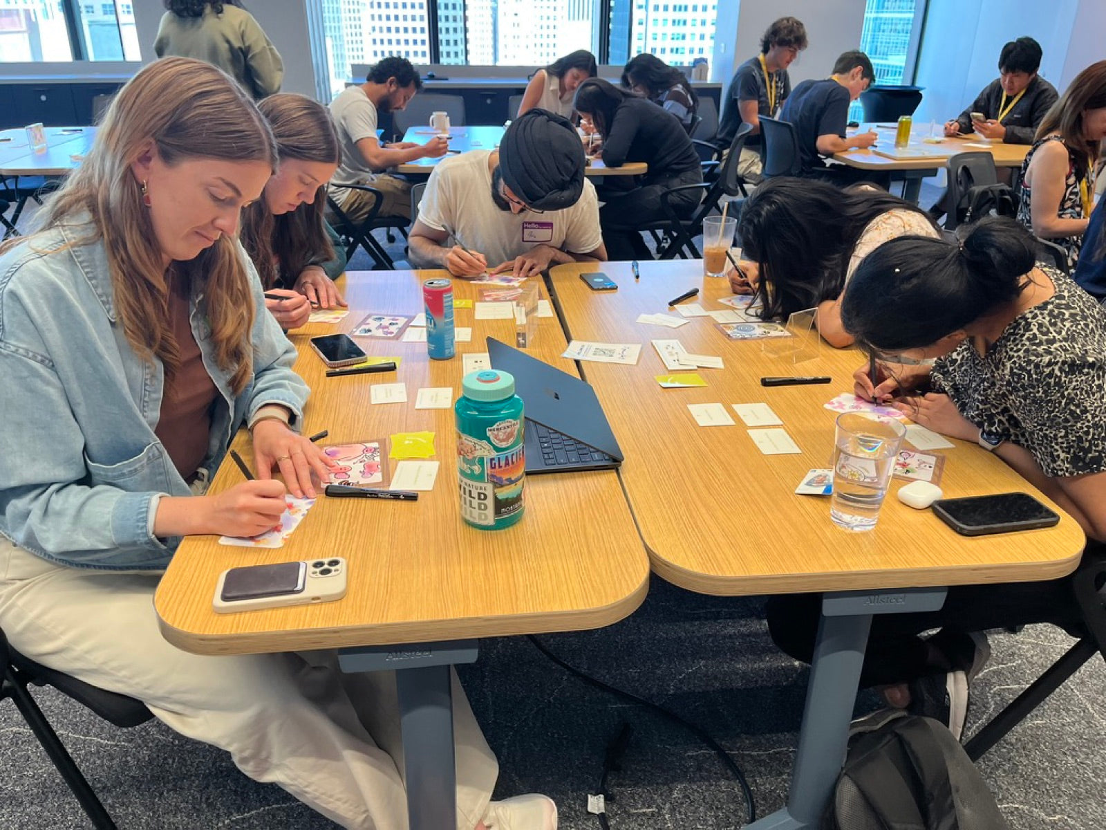 Workshop participants at long office tables, each doodling on a blob card