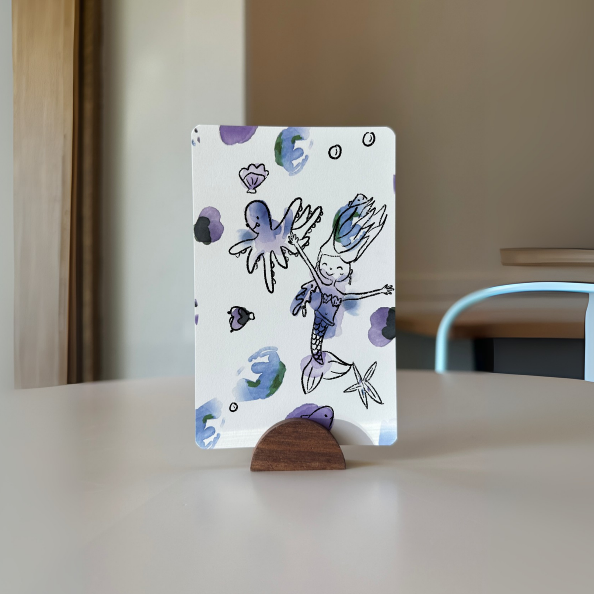 Doodled blob postcard displayed on a wooden stand