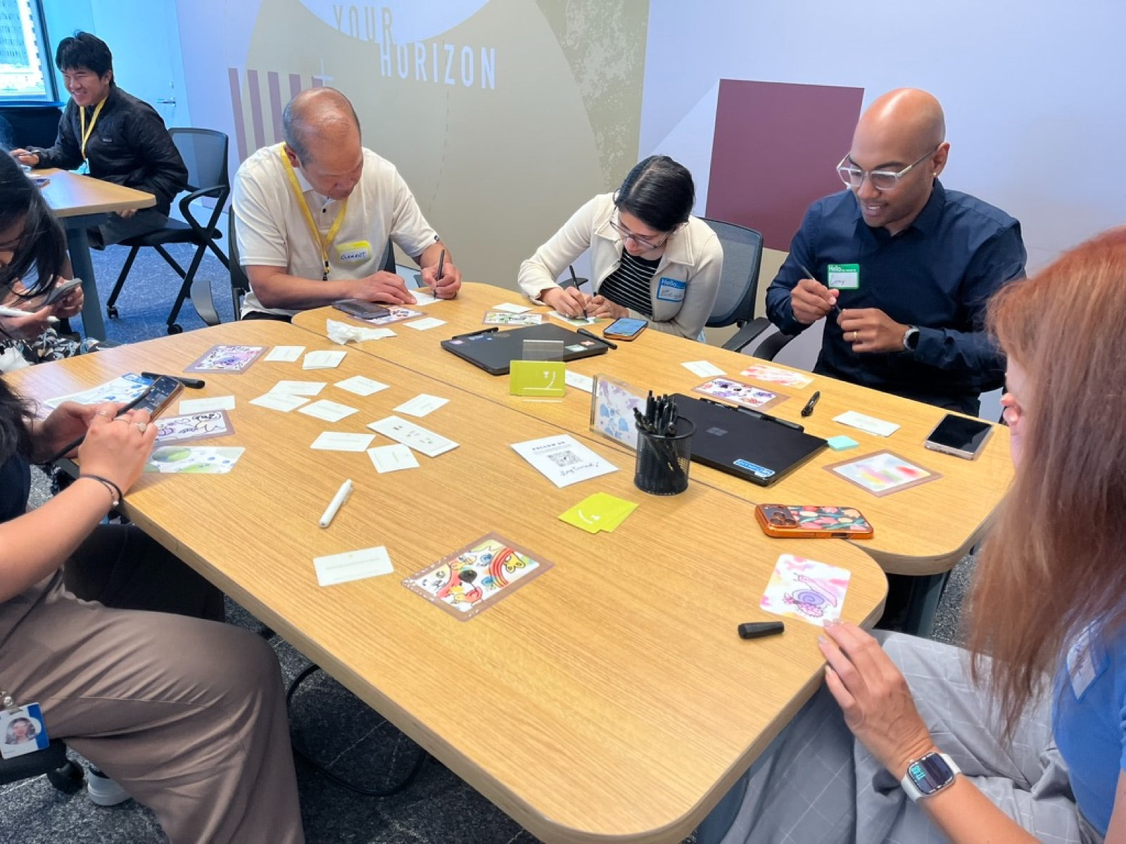 A team doodling on blob cards around a shared table at an office workshop